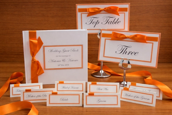 Bright vibrant orange wedding on the day stationery consisting of table names, place cards and a guest book