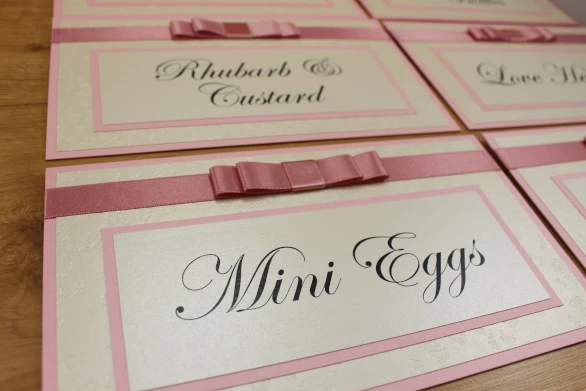 Wedding table name cards made in cream and blush pink with a layered ribbon bow